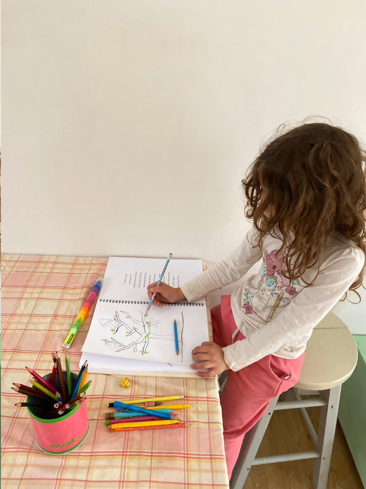 ילדה מציירת עץ בעזרת החוברת